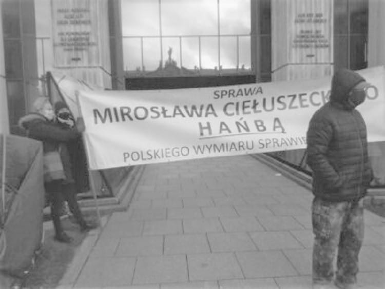 Protestujący trzymają transparent z napisem „Mirosława Ciełuszecko Hańba Polskiego Wymiaru Sprawiedliwości”, demonstrując przeciwko orzeczeniu polskiego sądu.