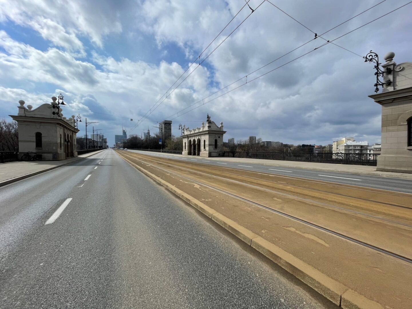 Pusty most warszawski z torami tramwajowymi, widocznymi detalami architektonicznymi i panoramą miasta.