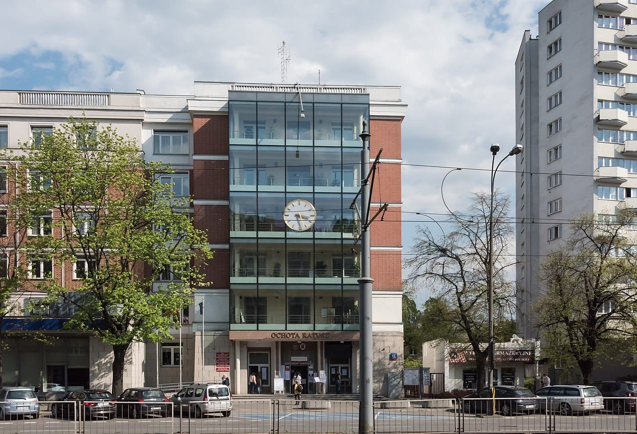 Ochota Rathaus w Warszawie, Polska. Nowoczesny budynek z dużą szklaną fasadą i zegarem.