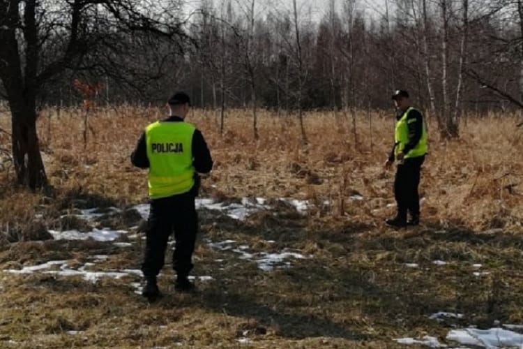 Dwóch polskich policjantów w żółtych kamizelkach bada miejsce zbrodni.