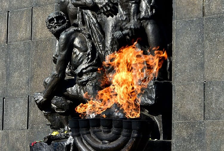 Wieczny płomień pod Pomnikiem Bohaterów Getta Warszawskiego, poruszającym upamiętnieniem ofiar Holokaustu.