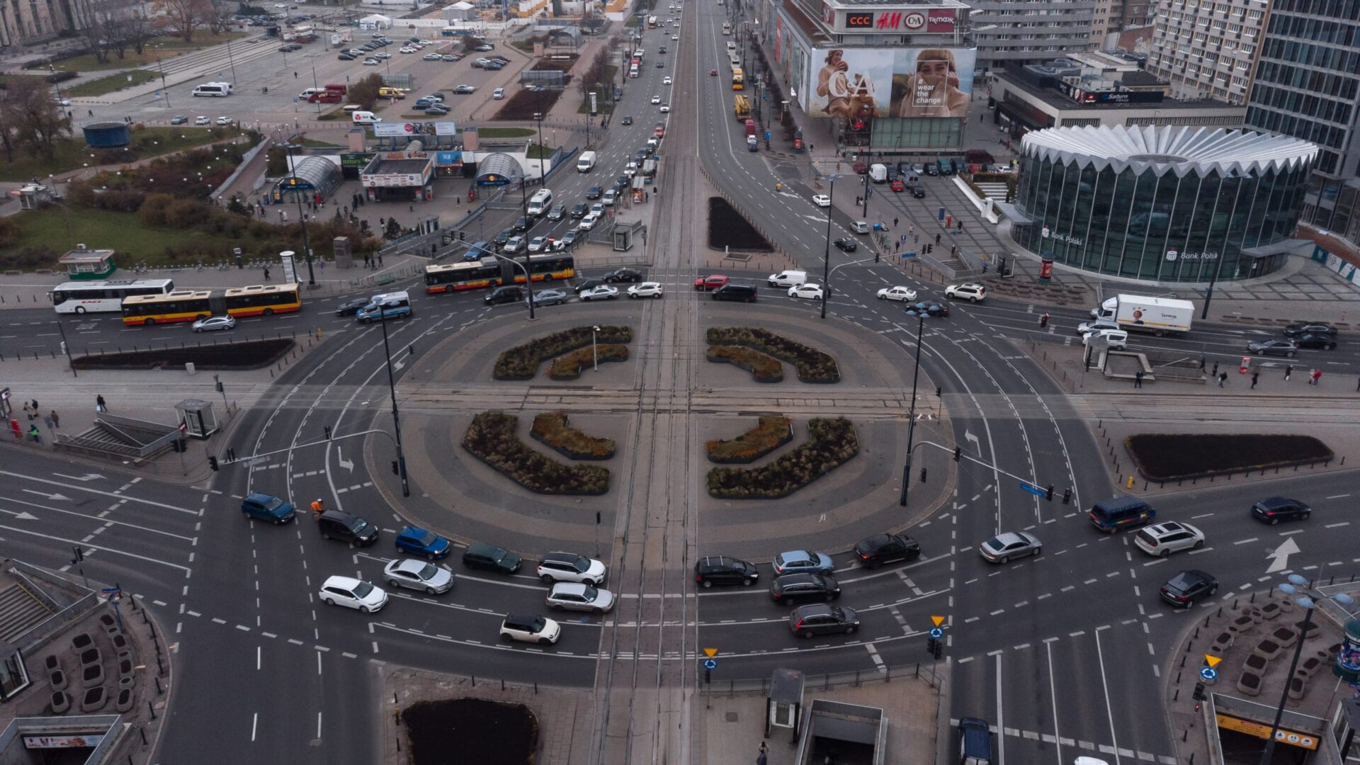 Widok z lotu ptaka na rondo w Warszawie, na którym widać samochody i autobusy.