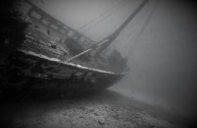 Zatopiony wrak statku na dnie oceanu, pokryty osadem.