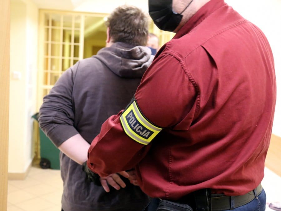 Policjant aresztujący podejrzanego na korytarzu.