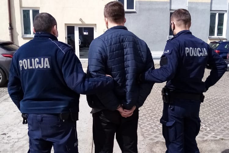 Dwóch polskich policjantów zatrzymuje podejrzanego. Na ich mundurach wyraźnie widać napis „POLICJA”.