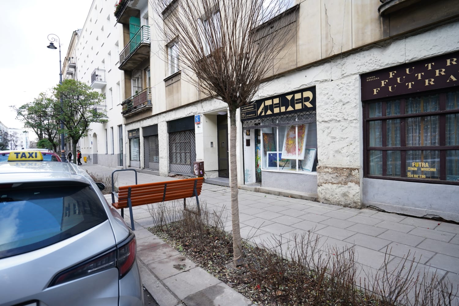 Scena uliczna Warszawy z galerią sztuki Atelier i taksówką