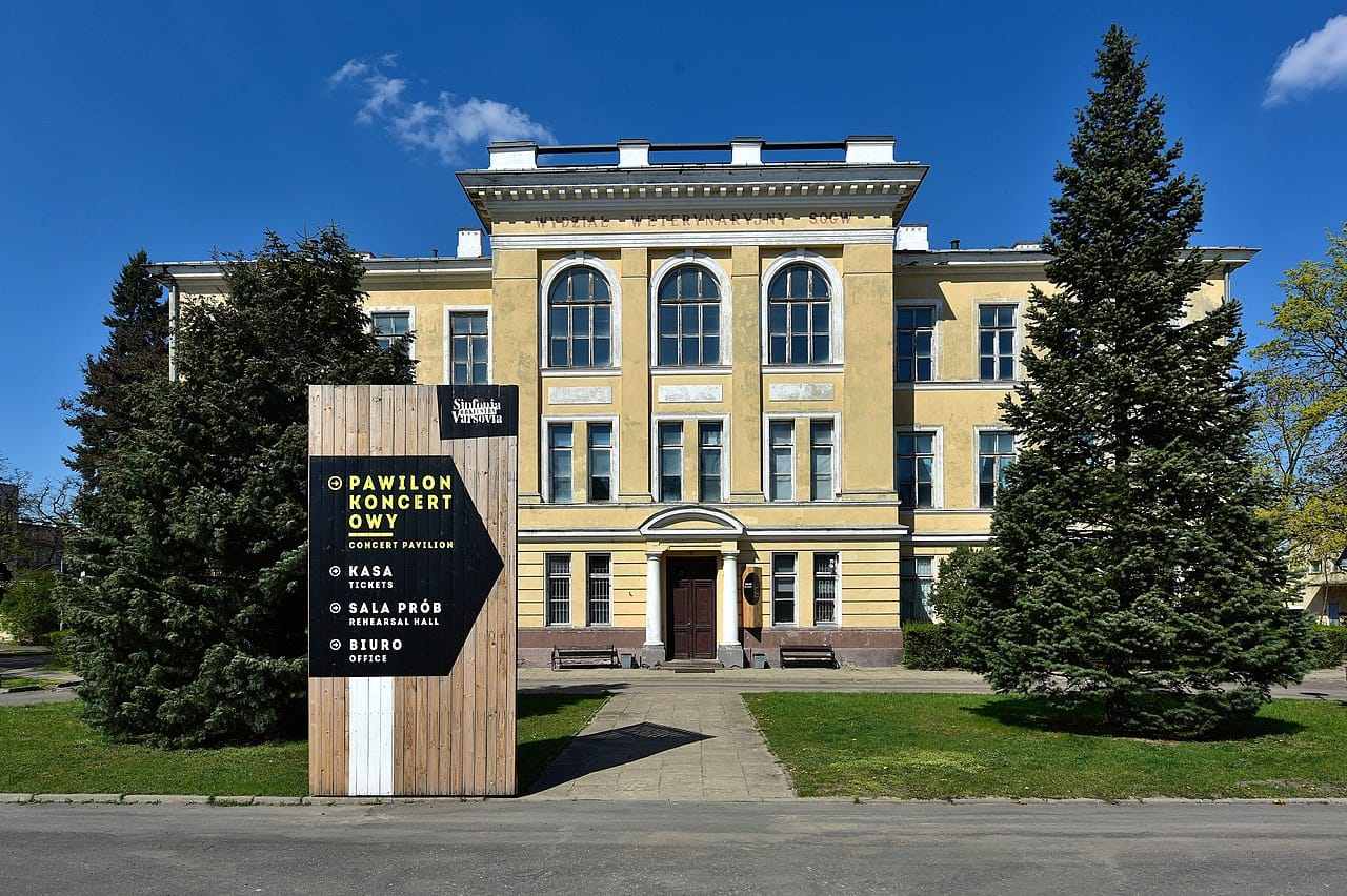 Pawilon Koncertowy w Warszawie: Widok zewnętrzny zabytkowego budynku, ukazujący tablice informacyjne o biletach, sali prób i biurze.