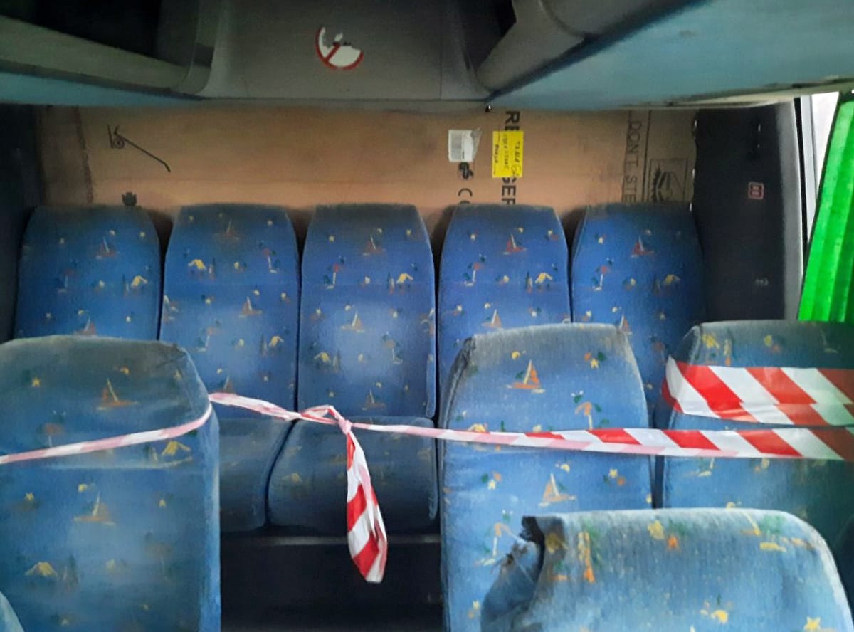 Zakurzone siedzenia autobusowe z taśmą ostrzegawczą. Wnętrze starego pojazdu.