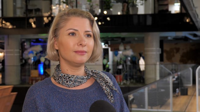 Portret blondynki ubranej w niebieski sweter i wzorzysty szalik.