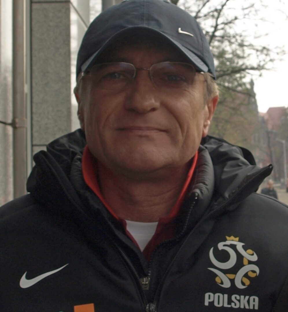 Zdjęcie trenera polskiej drużyny piłkarskiej Franciszka Smudy w czarnej kurtce Nike z logo reprezentacji Polski.