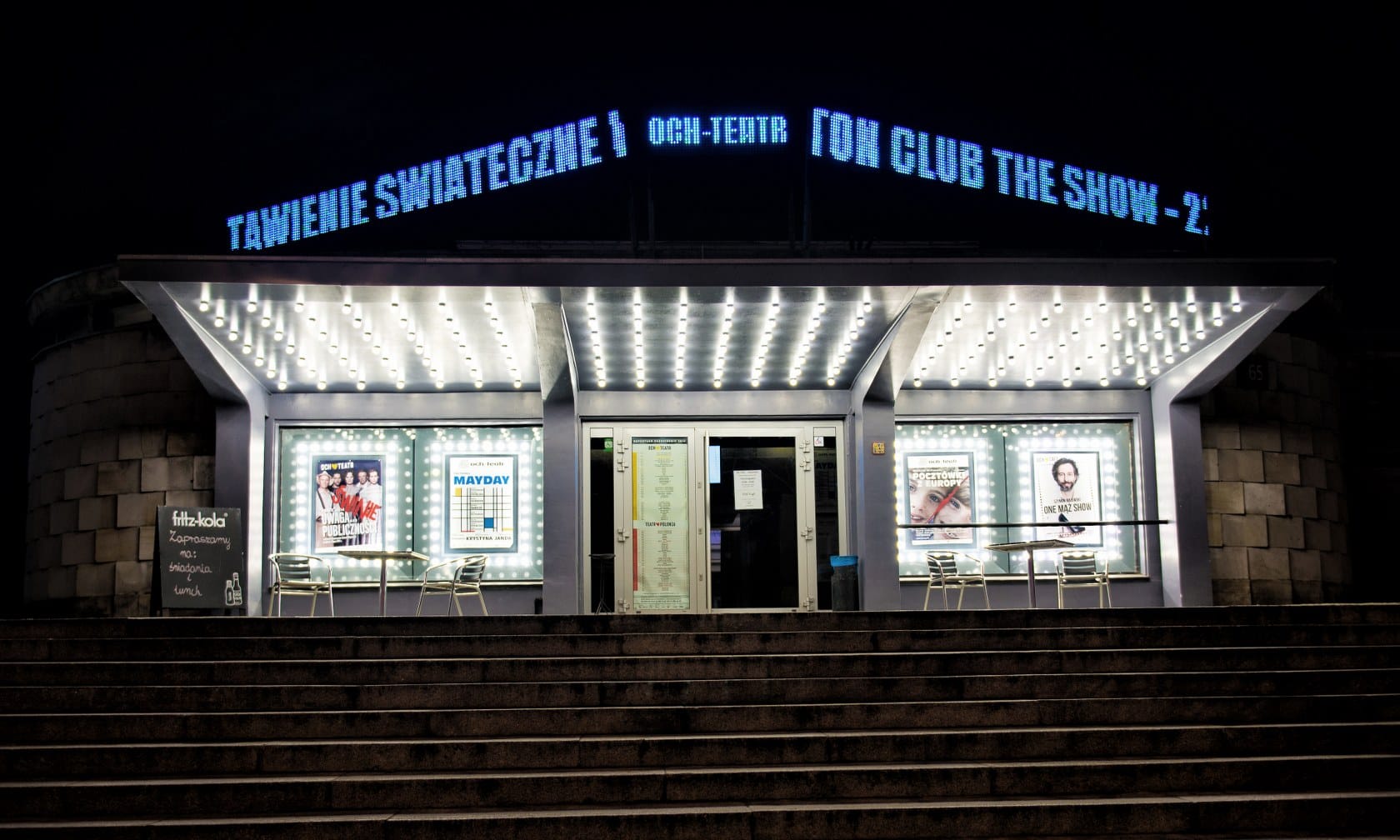 Widok nocny Och-Teatru, w tle widoczne podświetlane szyldy "Tanie Świąteczne" i "Con Club The Show - 2".