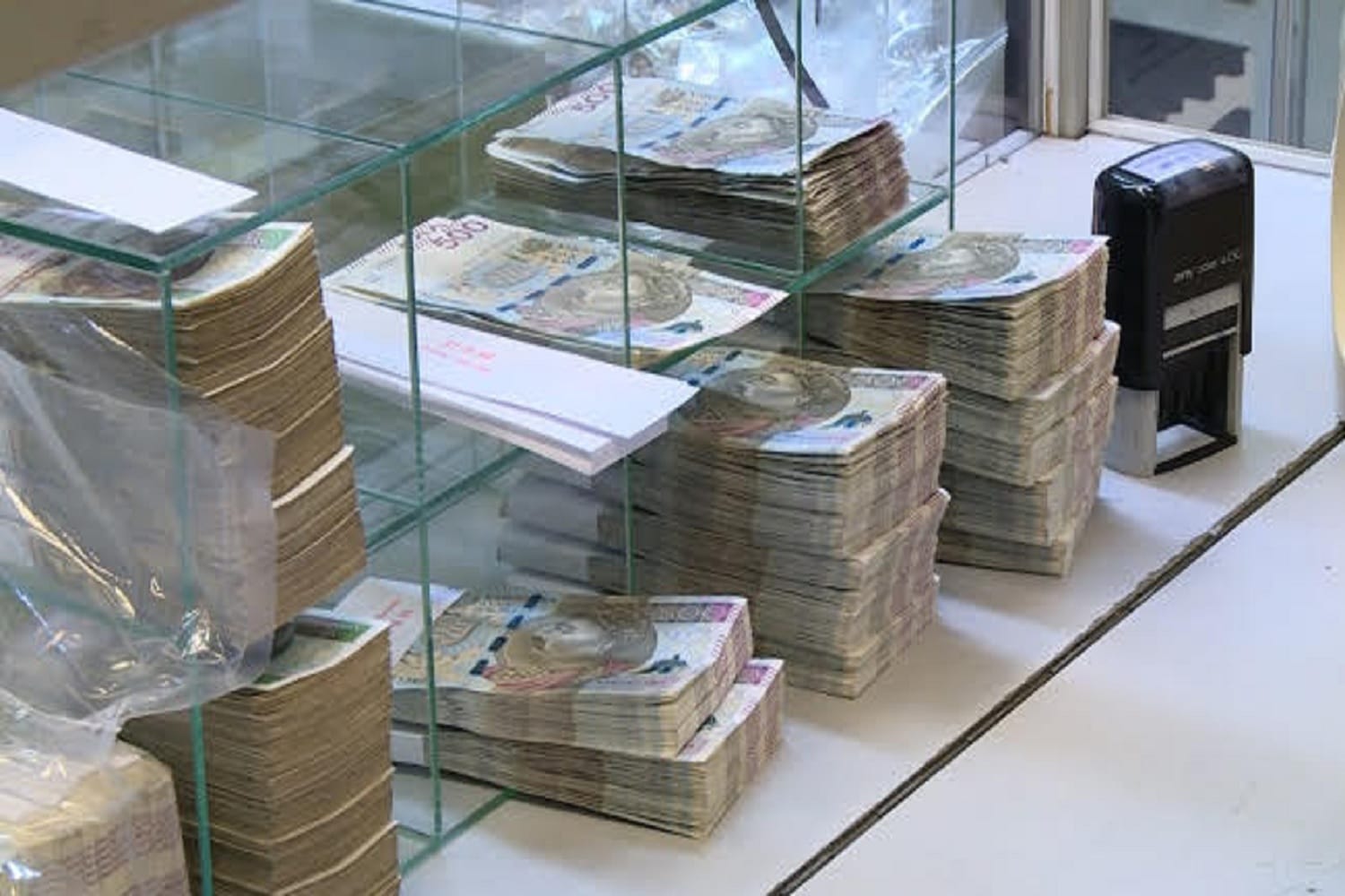 Stosy banknotów złotych polskich w szklanej gablocie.