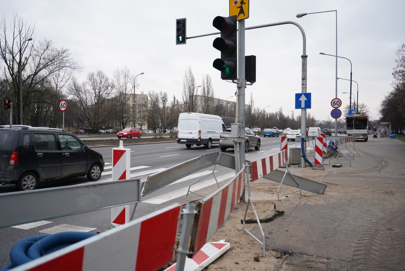 Budowa drogi z sygnalizacją świetlną i znakami ograniczenia prędkości. W tle widoczni są pracownicy.