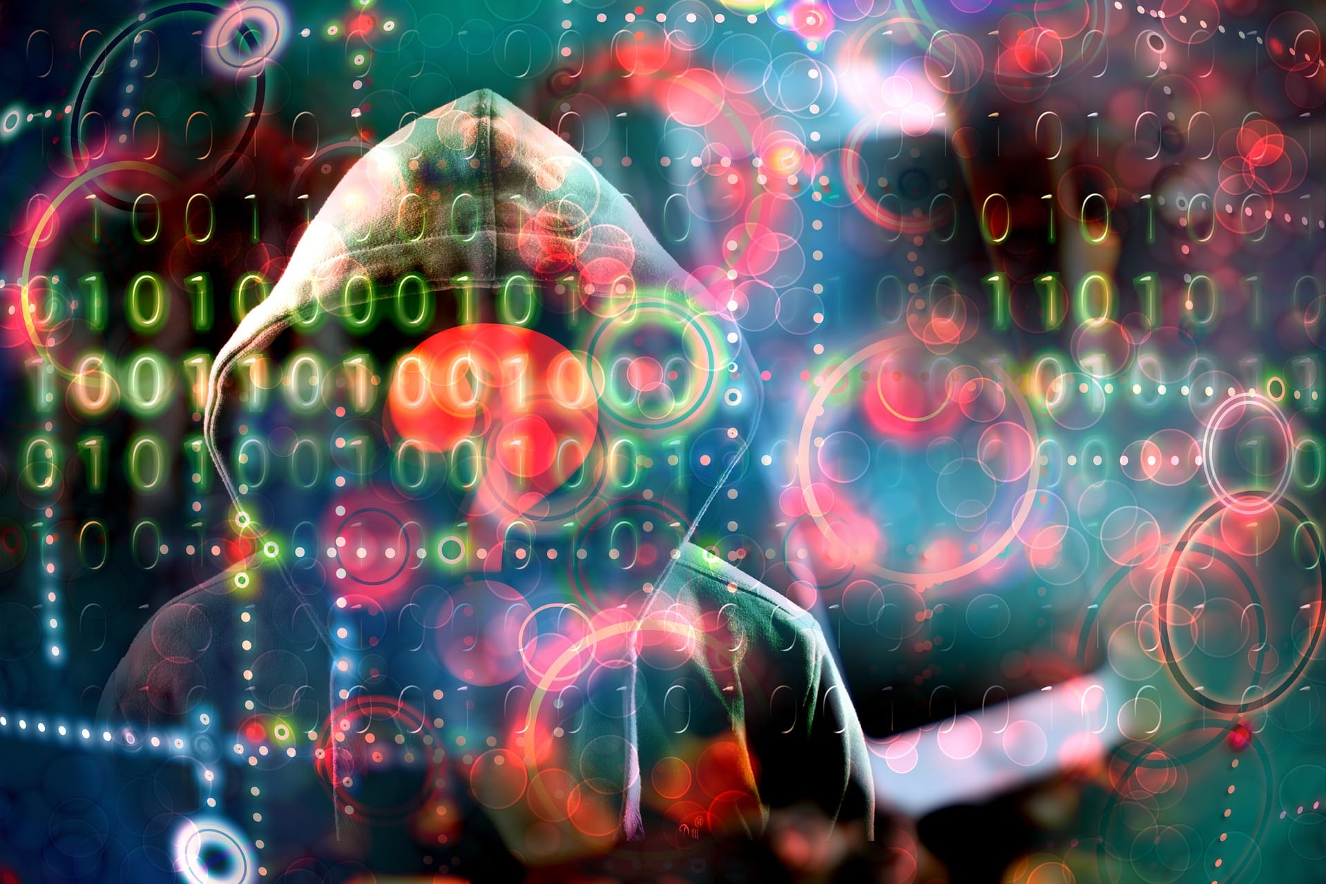 Zakapturzona postać zasłonięta kodem binarnym i rozmytymi okręgami, symbolizującymi zagrożenia cyberbezpieczeństwa.