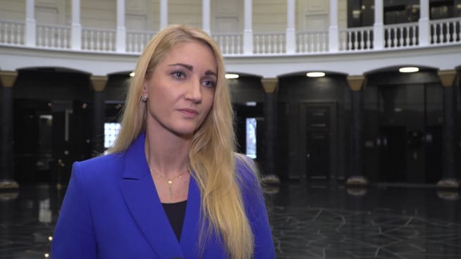 Blondynka w niebieskim blezerze udziela wywiadu.