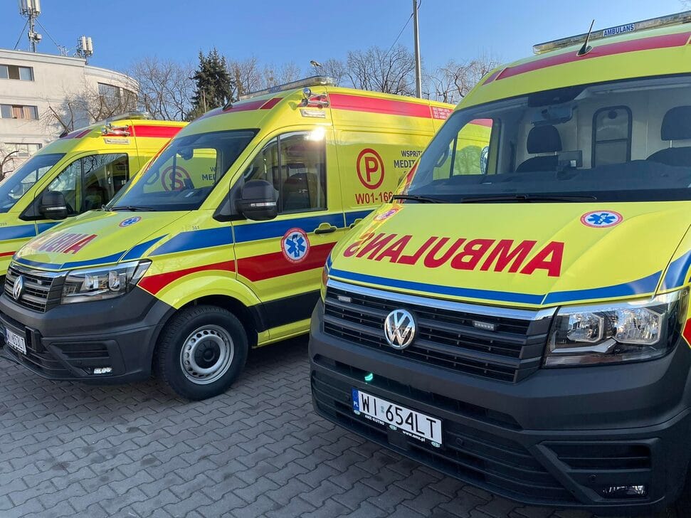 Trzy nowe ambulanse Volkswagena zaparkowane w rzędzie. Na pojazdach widać napis „Ambulans”.