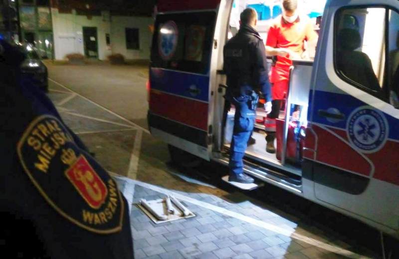 Pracownicy warszawskiego pogotowia ratunkowego udzielają pomocy pacjentowi w pobliżu karetki pogotowia.