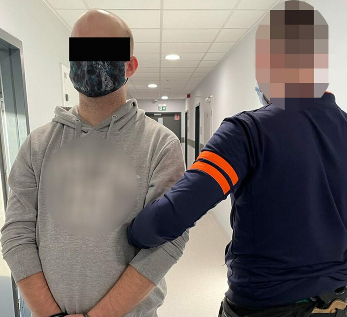 Policjant aresztujący podejrzanego na korytarzu szpitalnym.