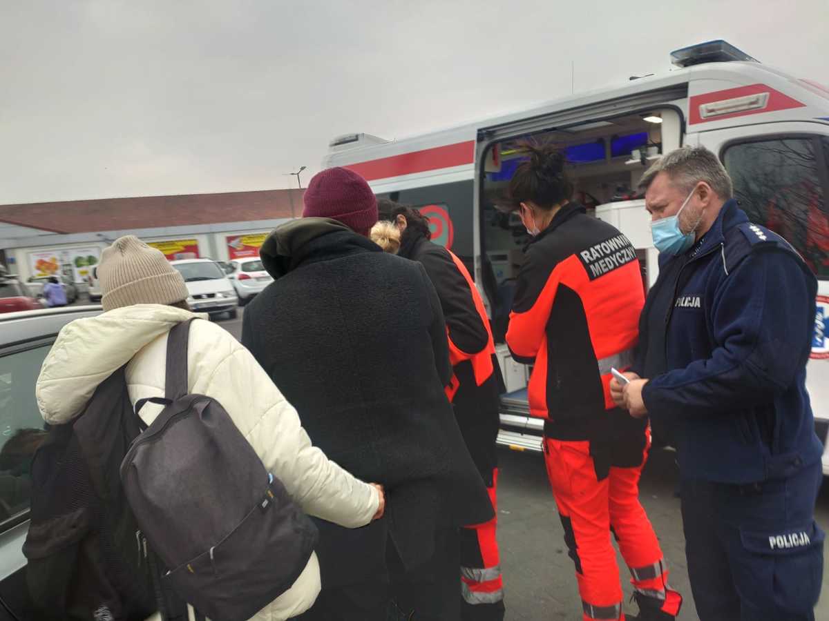 Ratownicy medyczni udzielają pomocy osobom znajdującym się w pobliżu karetki pogotowia. POLICJA