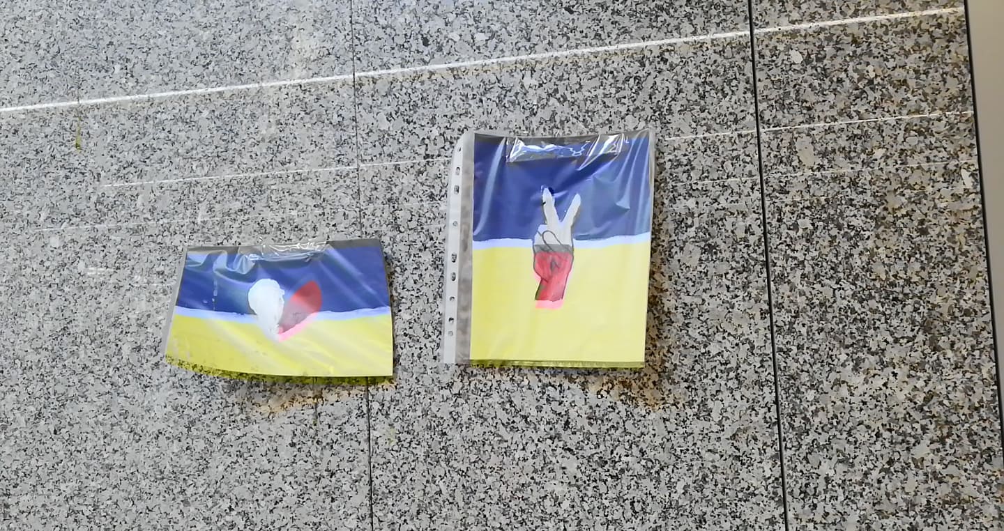 Dwa małe dzieła sztuki przedstawiające znaki pokoju i serca na granitowej ścianie. Użyto kolorów flagi Ukrainy.