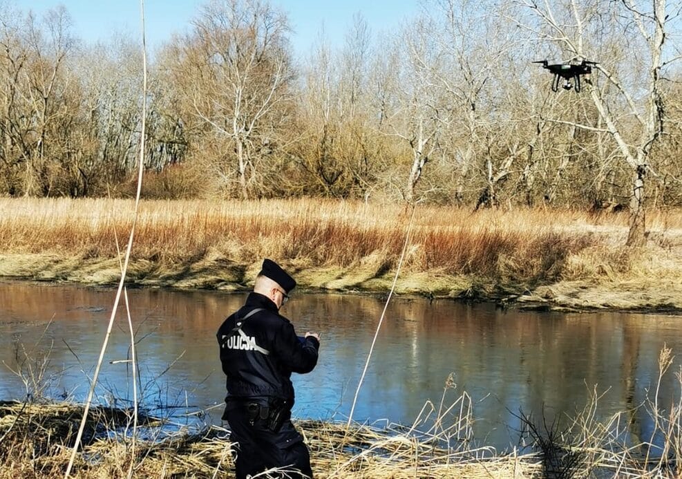 Policjant używa drona do przeszukiwania brzegu rzeki