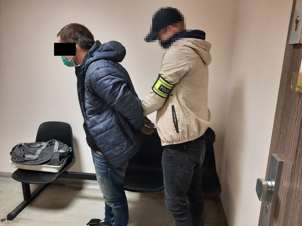 Policjant aresztujący podejrzanego w kajdankach.