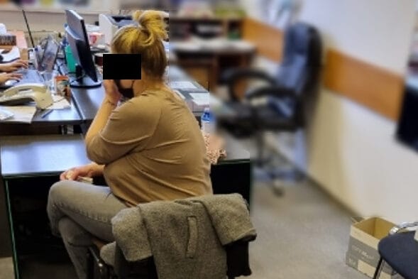 Kobieta pracuje przy komputerze w biurze i odbiera telefon.