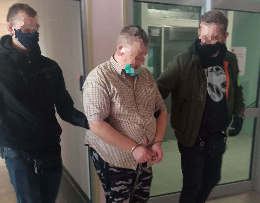 Dwóch policjantów eskortuje skutego mężczyznę. Aresztowanie.