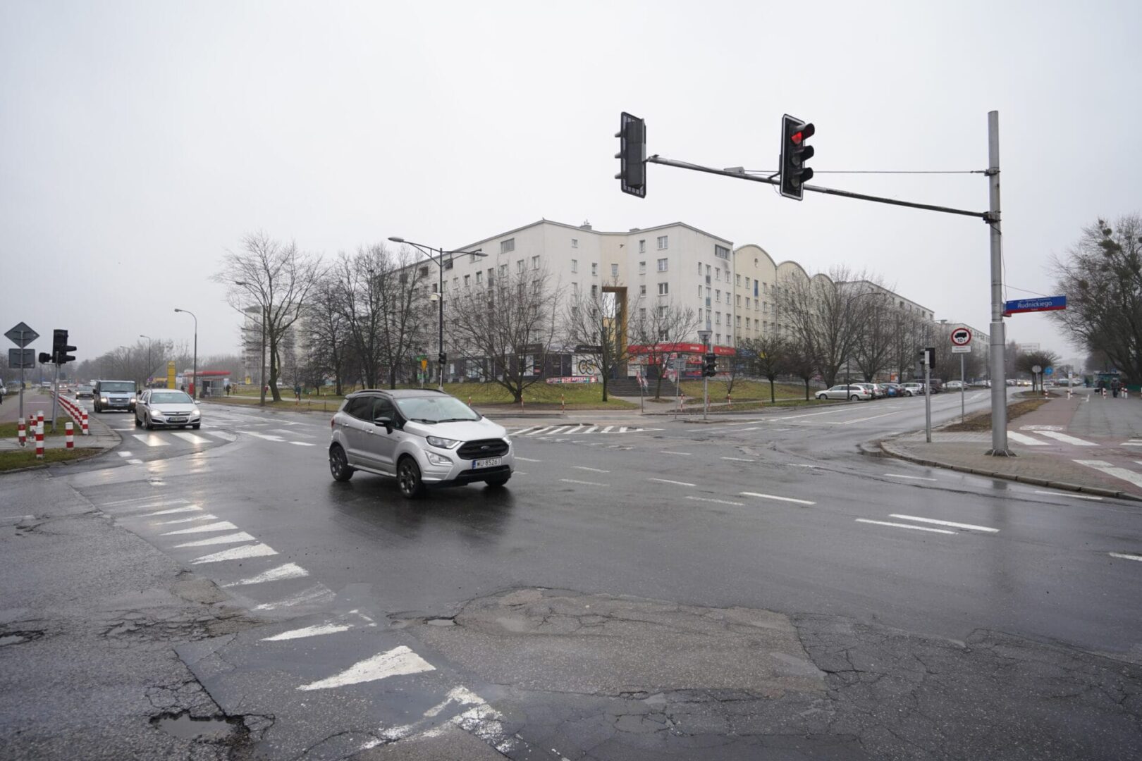 Deszczowy dzień na skrzyżowaniu w mieście. Srebrny SUV Ford EcoSport.