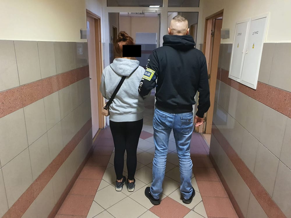 Policja eskortuje podejrzanego korytarzem.