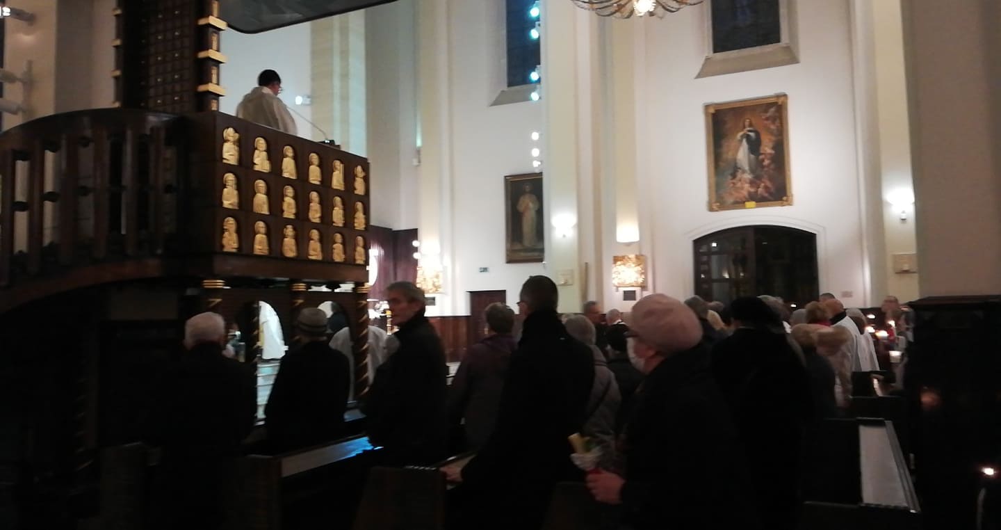 Uczestnicy mszy katolickiej z księdzem za amboną