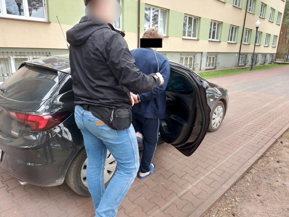 Policjant aresztujący podejrzanego w pobliżu samochodu