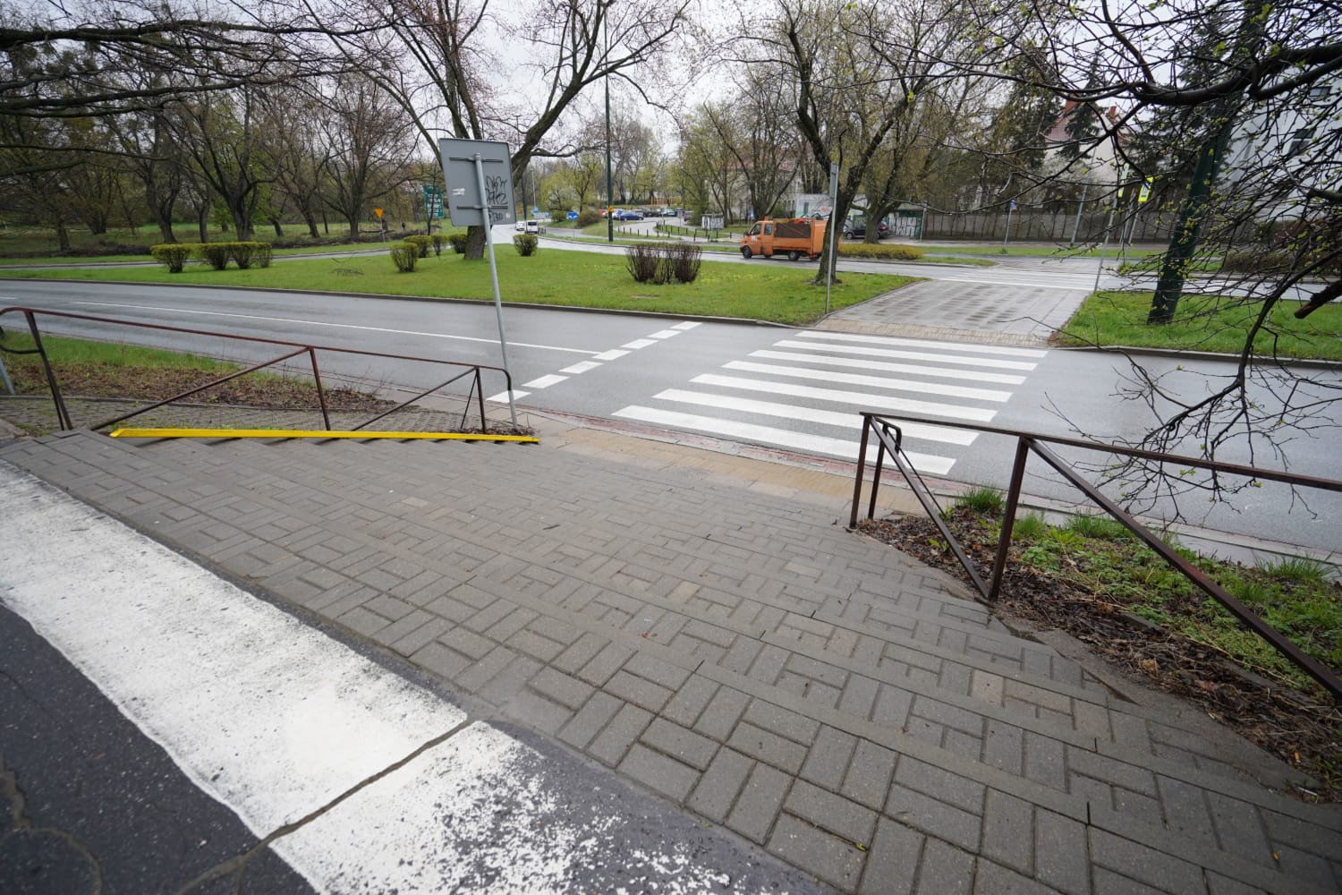 Przejście dla pieszych z obniżonym krawężnikiem i poręczami zapewniające dostępną trasę.