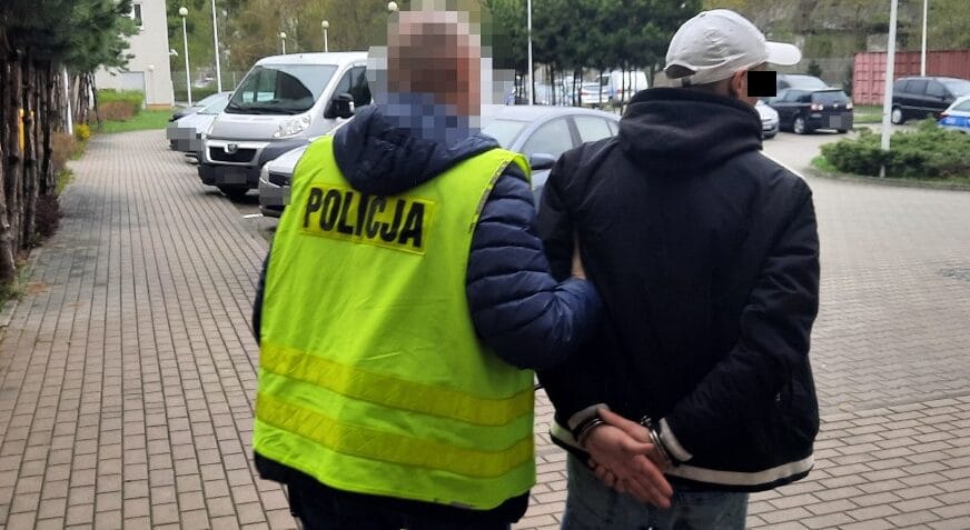 Policjant aresztujący podejrzanego, widoczne kajdanki. POLICJA.
