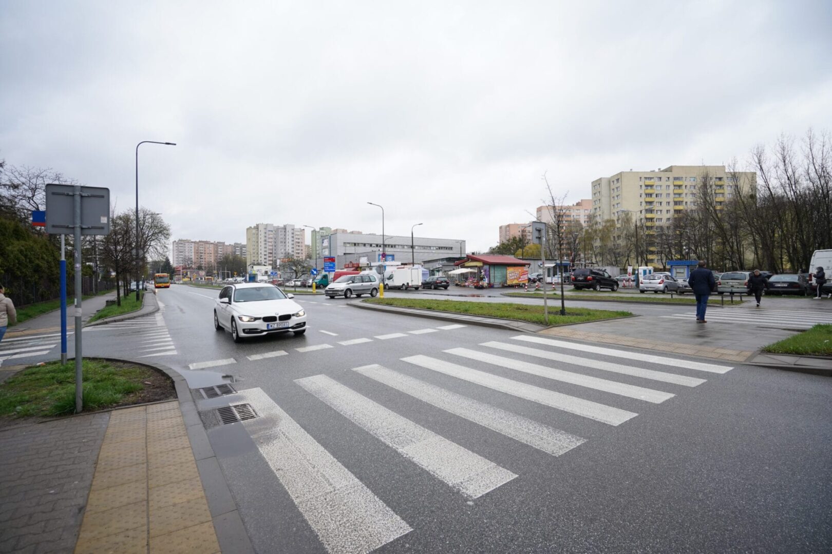 Piesi przechodzący przez ulicę w dzielnicy mieszkalnej, w której znajdują się budynki mieszkalne.