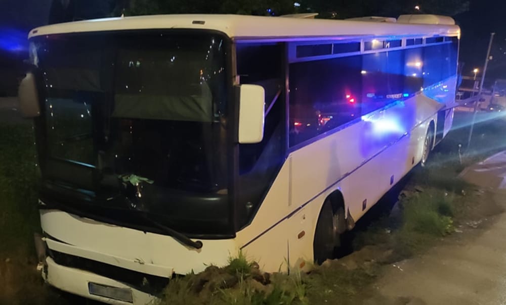 Uszkodzony autobus turystyczny w przydrożnym rowie w nocy