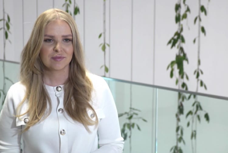 Uśmiechnięta blondynka w białym kardiganie.