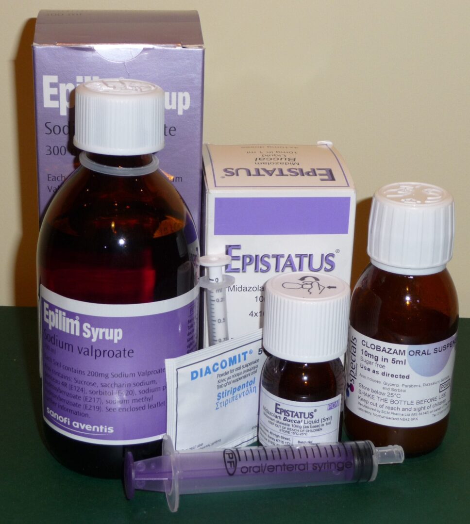 Różne leki na receptę, w tym syrop Epilim, Diacomit i Epistautus, są pokazane obok strzykawek doustnych.