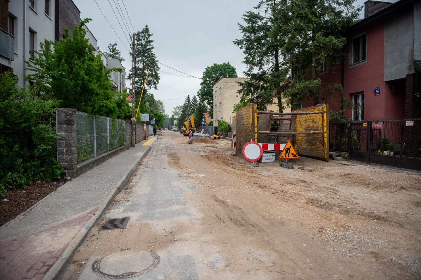 Plac budowy drogi z koparkami i znakami ostrzegawczymi.