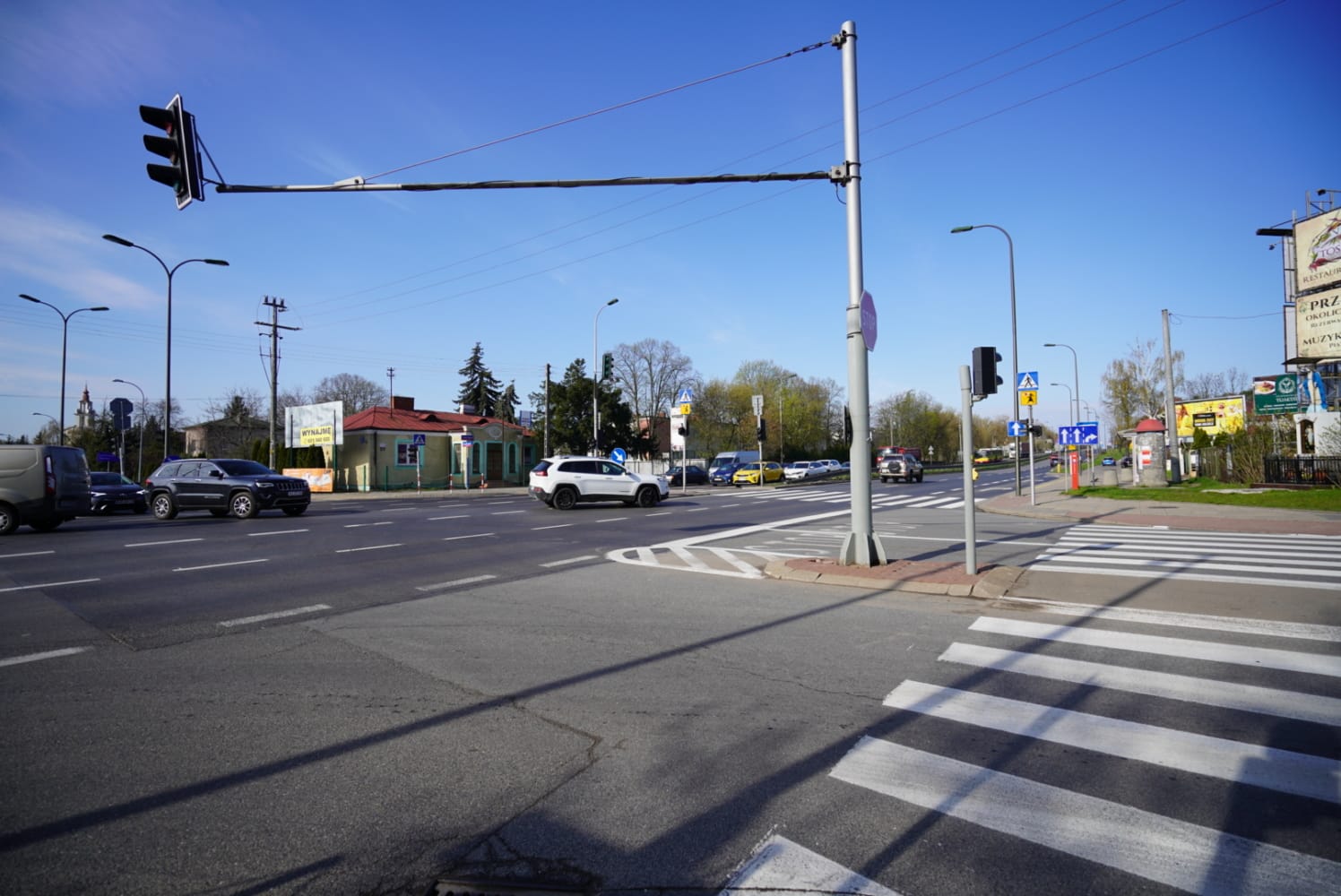 Ruchliwe polskie skrzyżowanie z sygnalizacją świetlną, przejściem dla pieszych i samochodami.