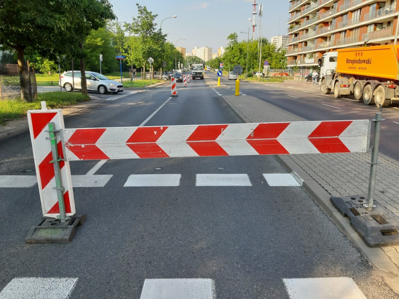 Droga zamknięta z czerwonymi i białymi pasami i przejściem dla pieszych. Trwają prace budowlane.