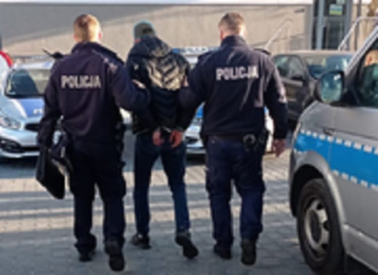 Dwóch polskich policjantów aresztuje podejrzanego, na jego mundurach widać napis POLIJA.