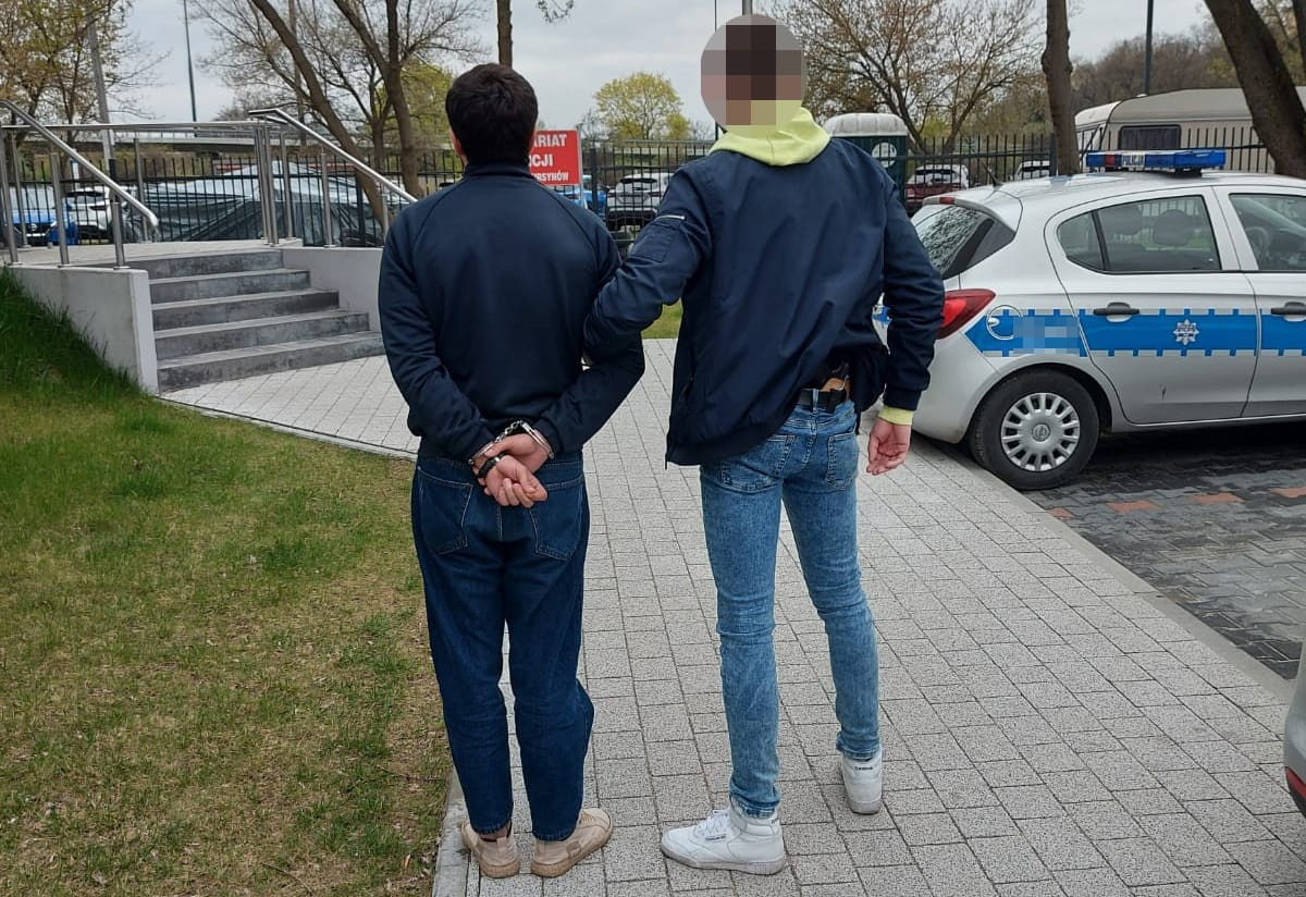 Policjant aresztujący podejrzanego w kajdankach.