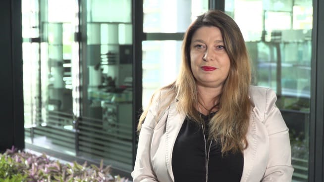 Portret kobiety w beżowej marynarce na rozmytym tle biura.