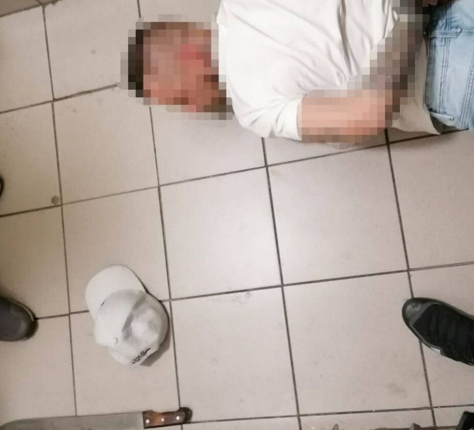 Aresztowany mężczyzna leży na podłodze w łazience, ma związane ręce. Maczeta i kapelusz są w pobliżu.