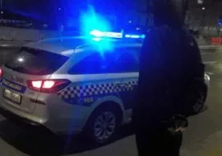 Policjant stojący obok radiowozu w nocy