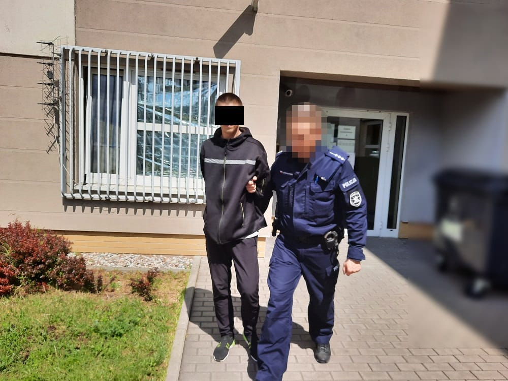 Policjant aresztujący podejrzanego przed budynkiem