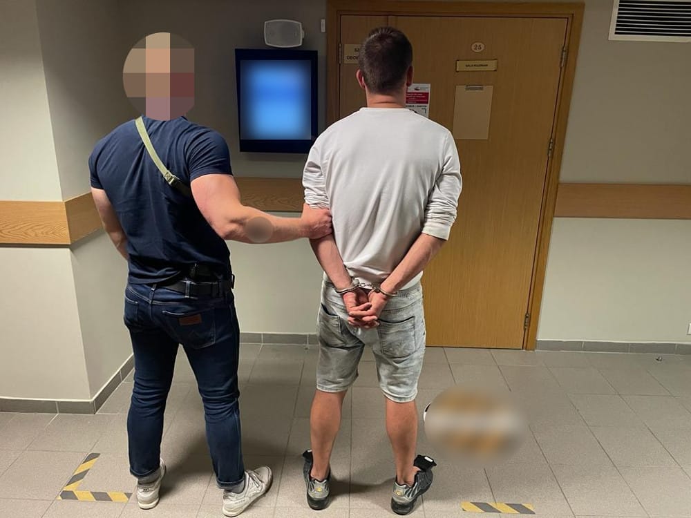 Policjant aresztujący podejrzanego w kajdankach.