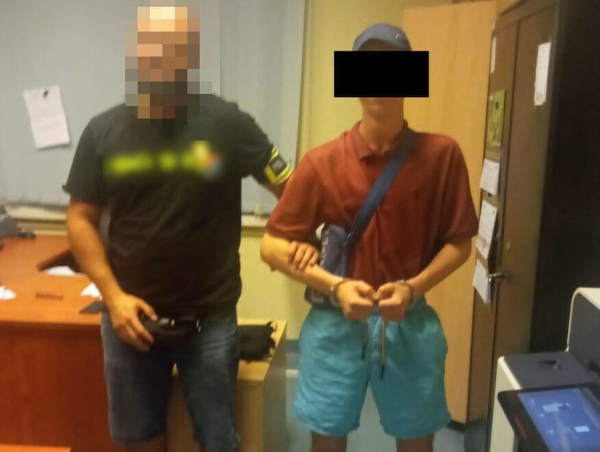 Policjant aresztujący młodego mężczyznę w kajdankach