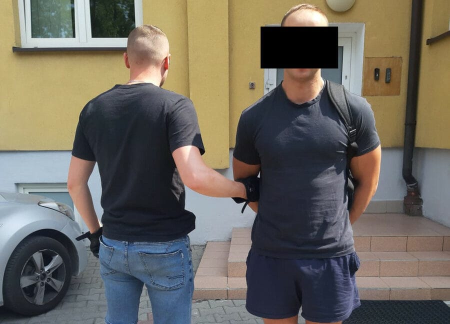 Policjant aresztujący podejrzanego przed budynkiem.